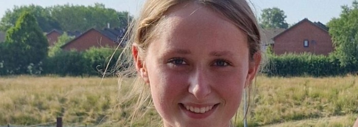 Sophia stood at running track with medals around her neck. 